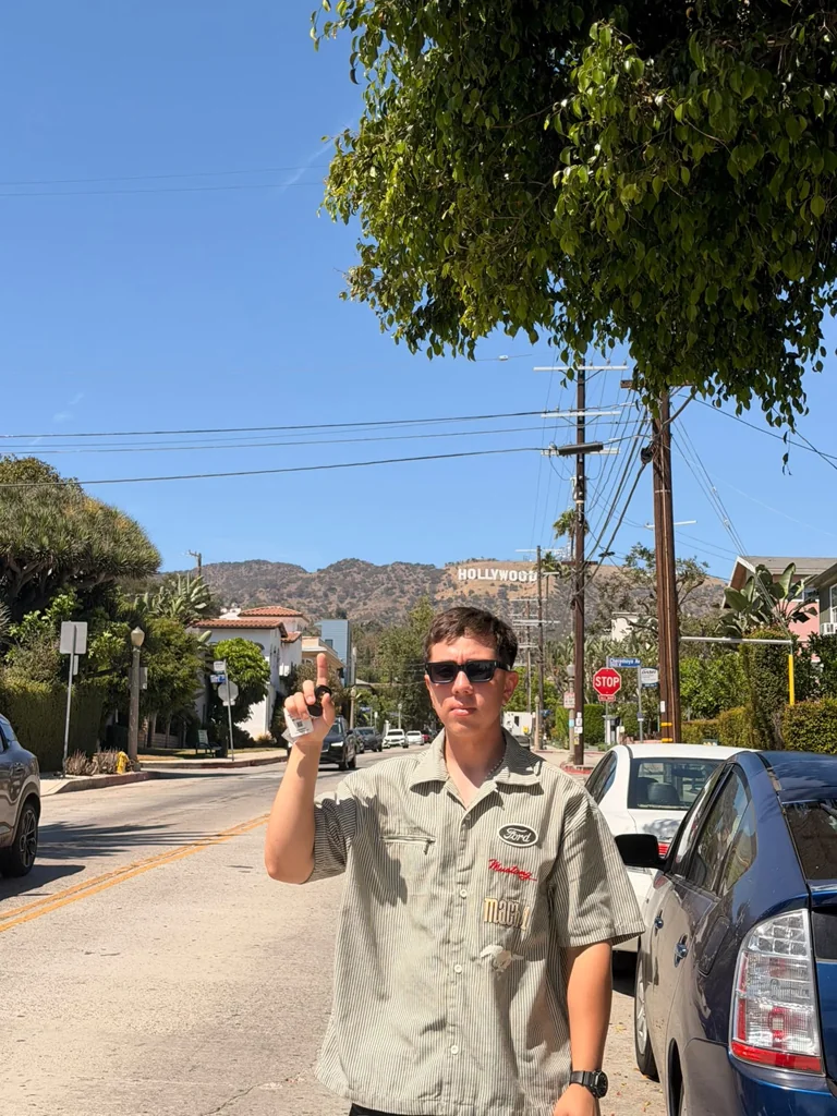 Freddy Flores wearing sunglasses with the Hollywood sign behind him